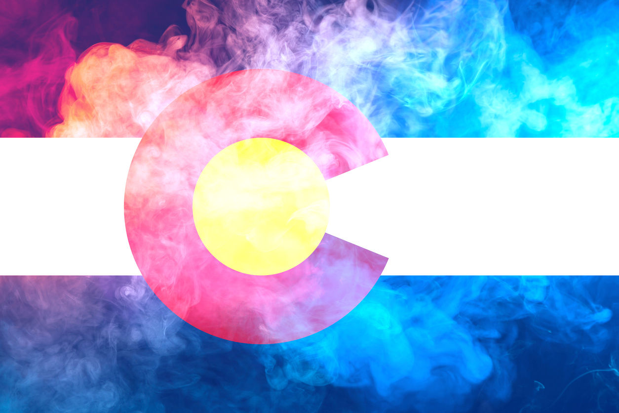 The national flag of the US state Colorado in against a gray smoke on the day of independence in different colors of blue red and yellow. Political and religious disputes, customs and delivery.